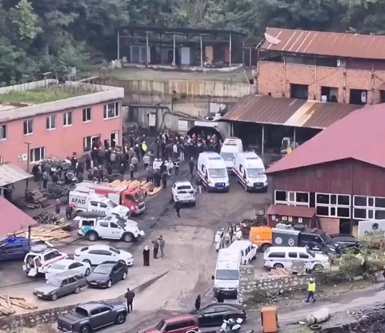 Maden ocağı girişi önünde toplanmış kalabalık; ambulanslar, AFAD araçları ve itfaiye aracı park halinde.