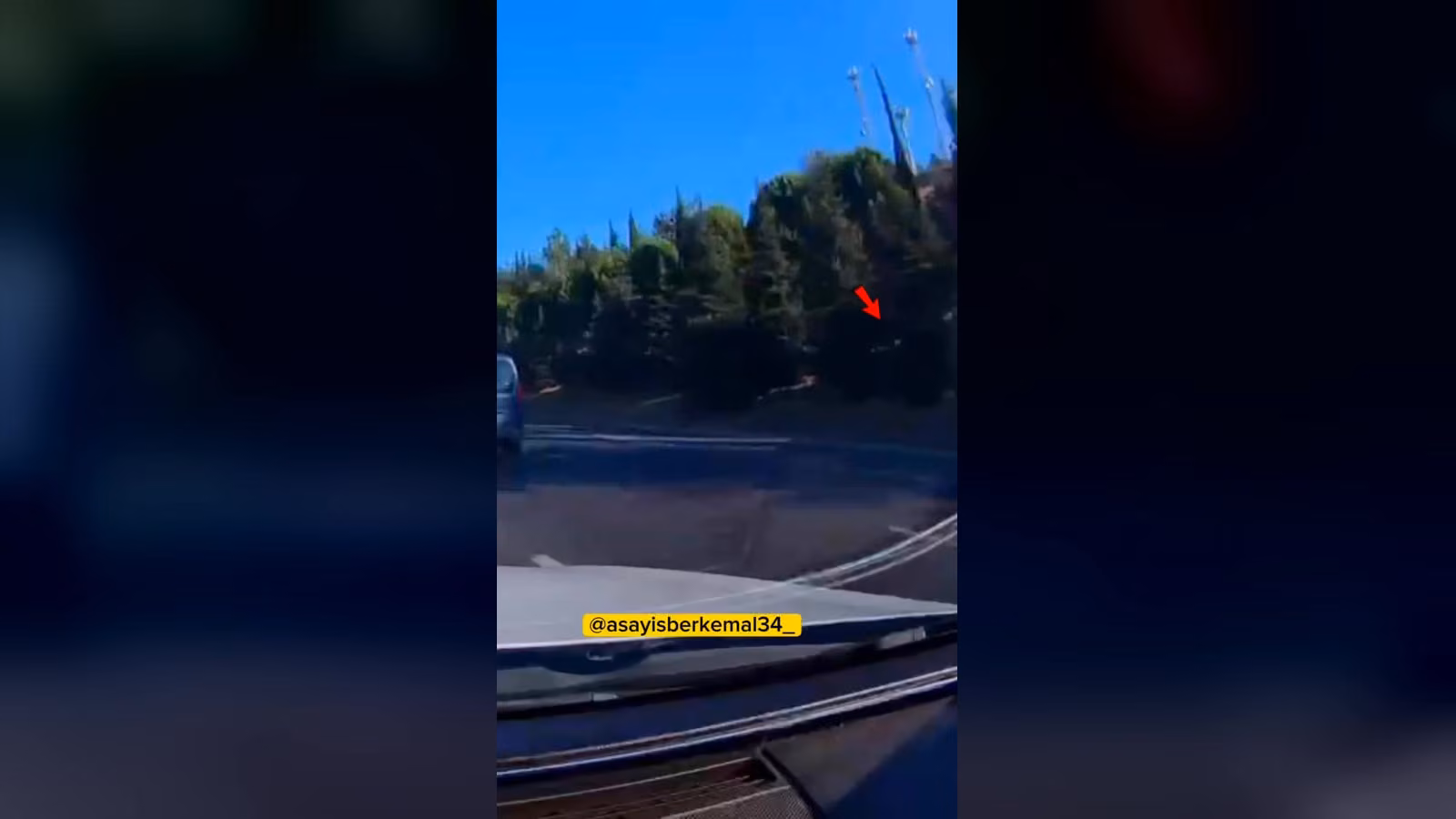 Otoyoldan araç içinden çekilmiş bir kare: sol kenarda mavi bir araç, sağda ağaçlık, bariyerler ve kırmızı bir ok ağaçların ön