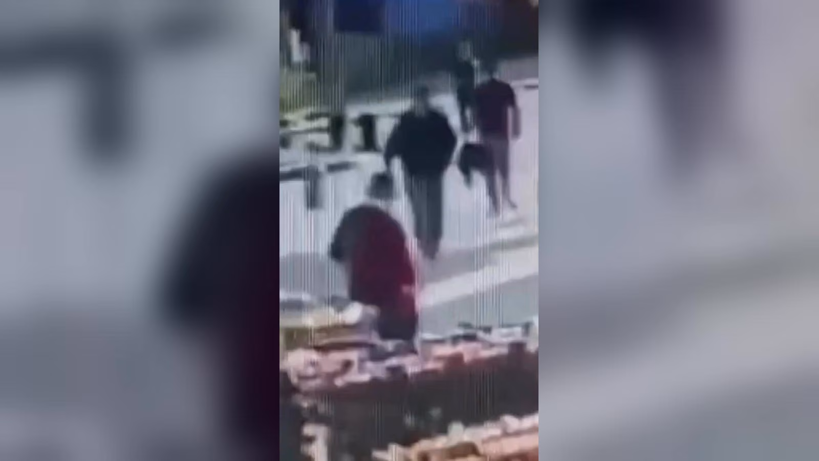Kaldırımda yürüyen birkaç kişi; önde kırmızı üstlü bir kişi, arkada koyu renk kıyafetli kişiler var. Görüntü bulanık.