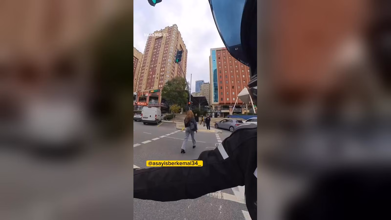 Motosiklet sürücüsünün kaskından görülen manzara: yaya geçidinde karşıya yürüyen, uzun saçlı bir kadın.