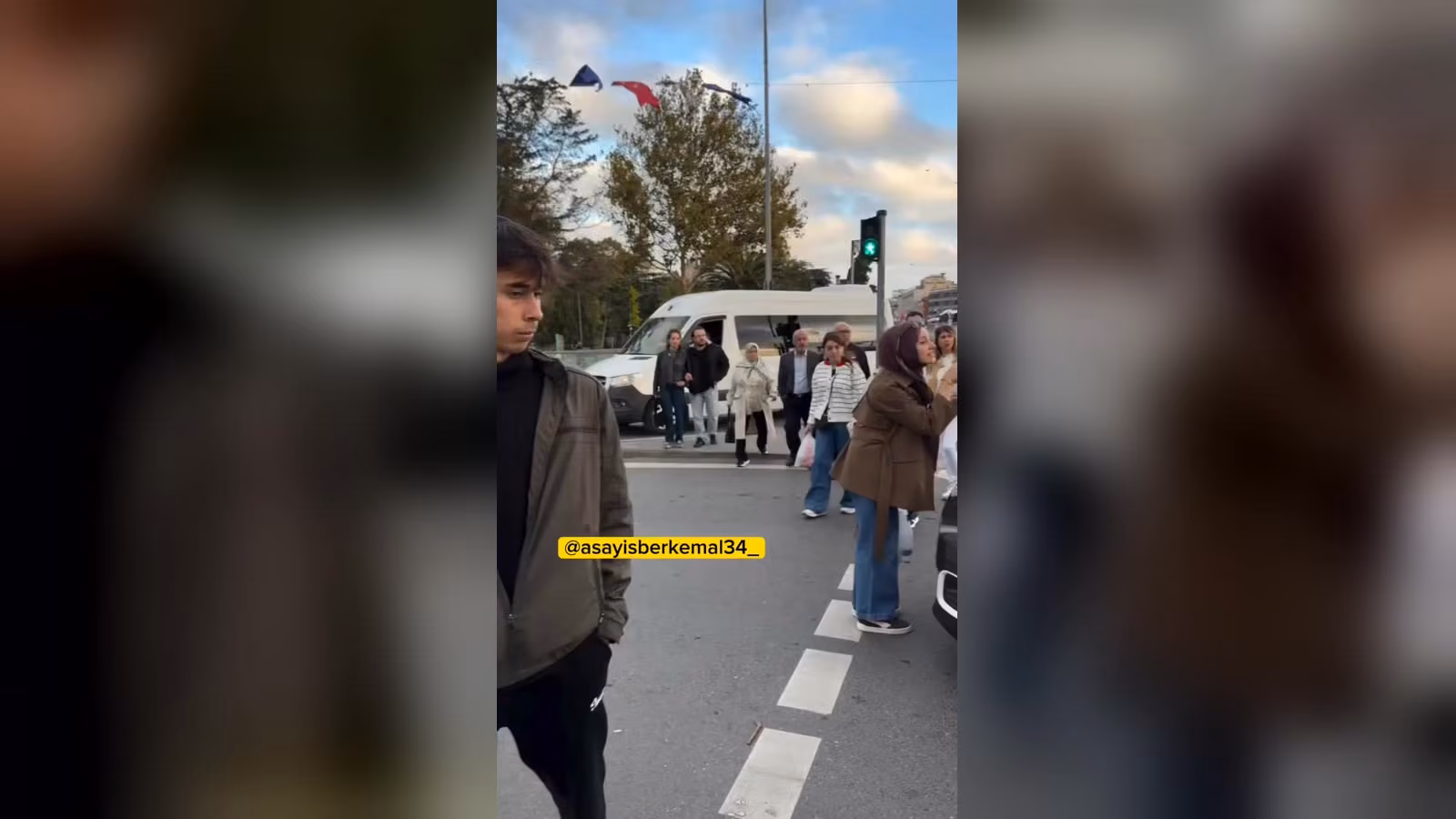 Yeşil yanan yaya ışığında karşıdan karşıya geçen insanlar; yanda beyaz bir minibüs ve sağda kısmen görünen bir araç.