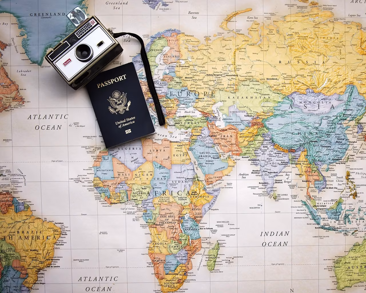 Dünya haritasının üzerinde eski bir Kodak fotoğraf makinesi ve Amerika Birleşik Devletleri pasaportu duruyor.