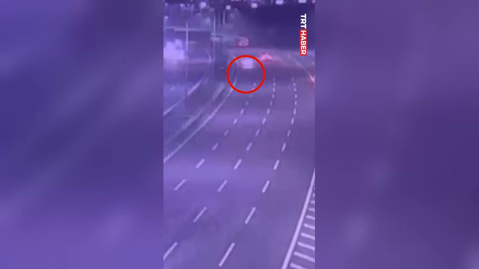 Mor tonlu görüntüde çok şeritli bir yol; kırmızı daireyle işaretlenmiş bir araç, kesikli şerit çizgileri ve kenar bariyerleri